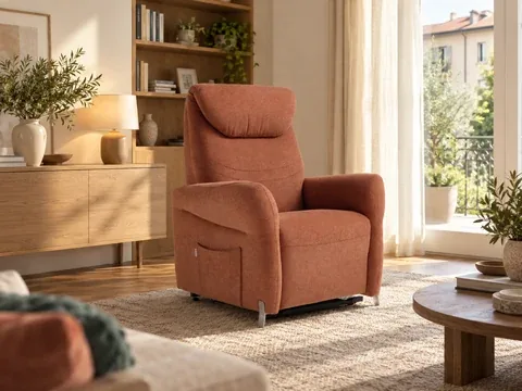 Poltrona alzapersona Raya terracotta accanto al divano in un soggiorno luminoso